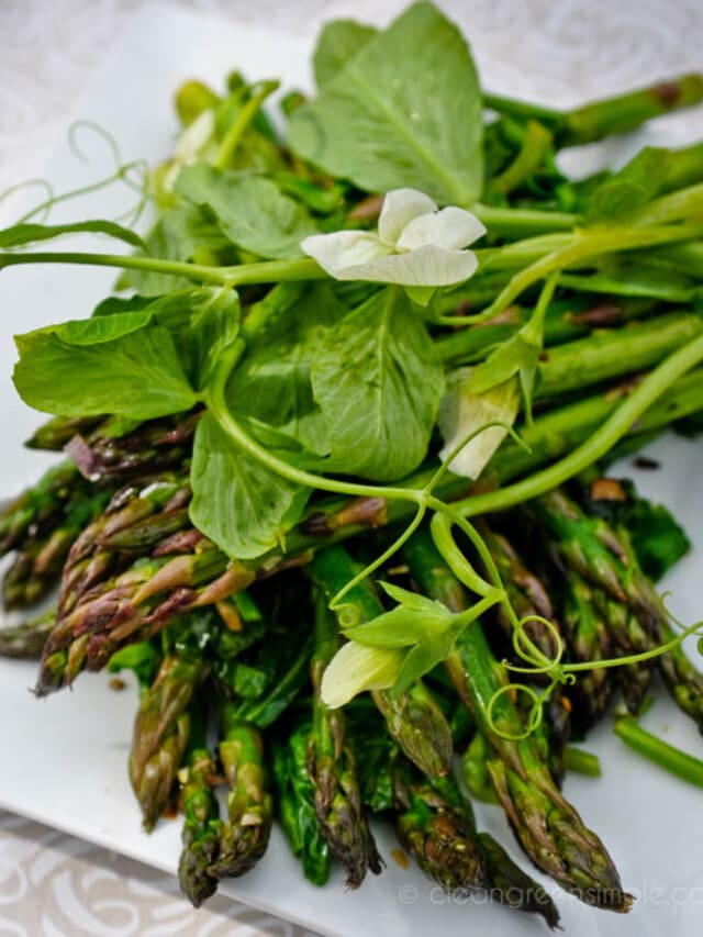 Asparagus salad topped with pea tendrils on a plate.