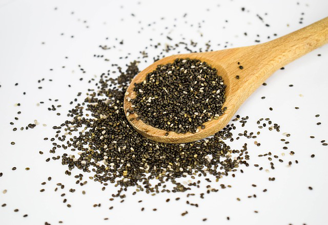 Chia seeds spilling out of a wooden spoon.