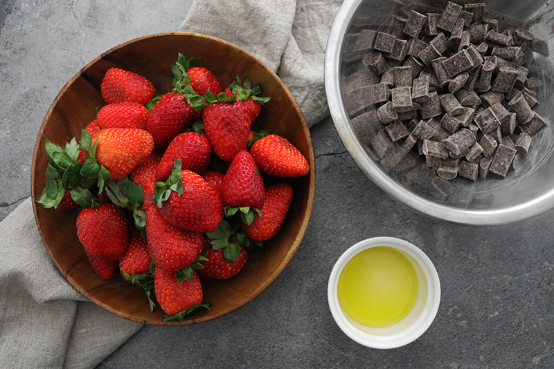 Strawberries in a bowl, with vegan chocolate and oil