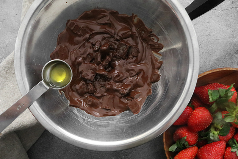 adding oil to melted chocolate in a bowl