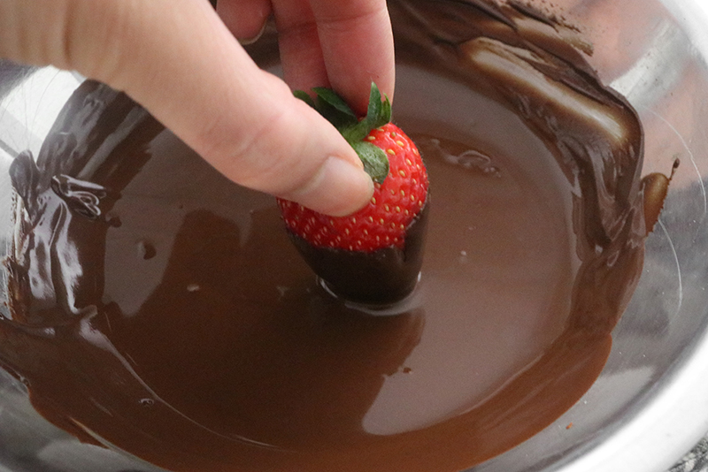 Dipping a strawberry into a bowl of chocolate