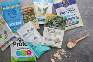 Several vegan protein powders with a wooden spoon