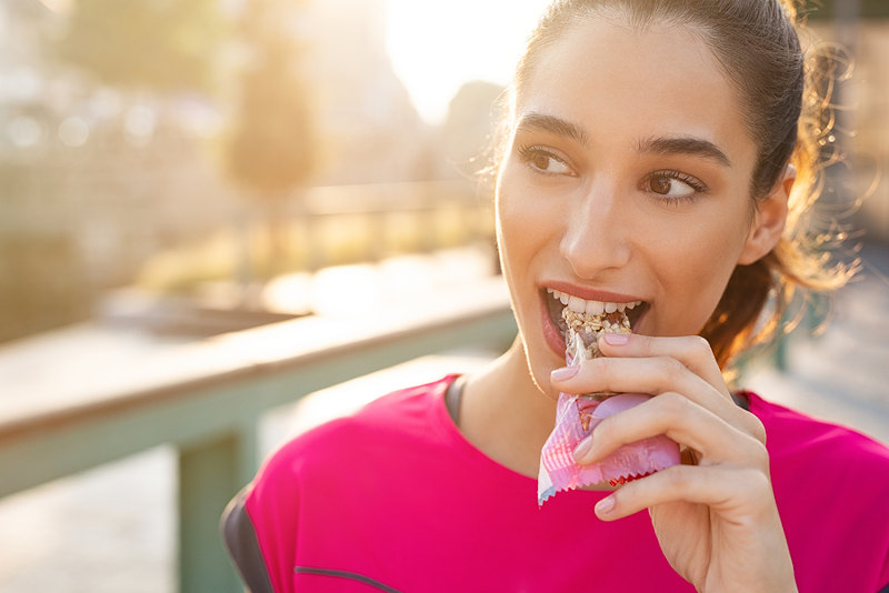 Athletic woman eating a protein bar