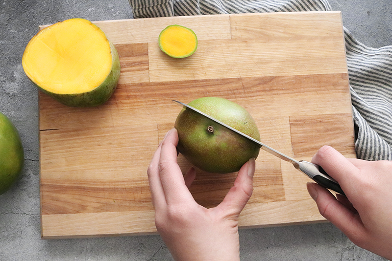 top view of slicing a mango on a cutting board