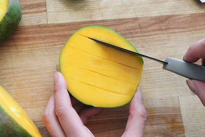 scoring across the flesh of a mango with a paring knife