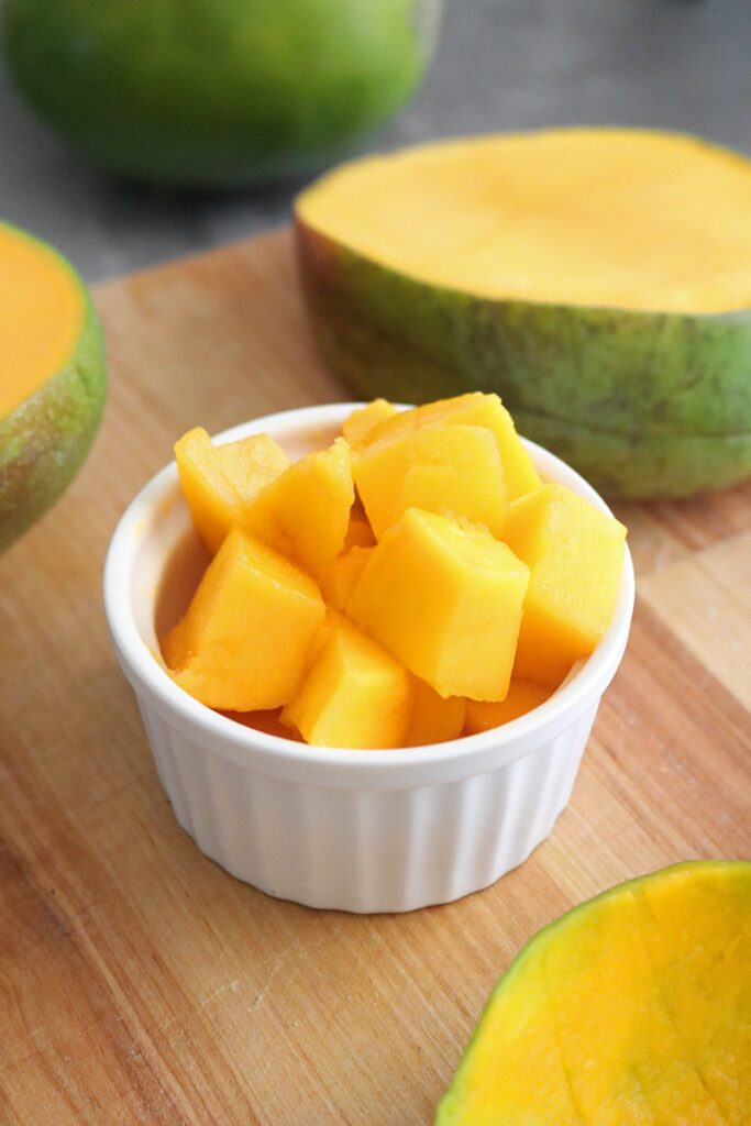 cubed mango in a ramekin on a cutting board