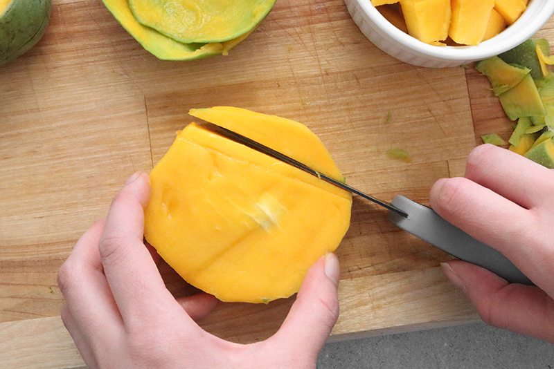 slicing off flesh of a mango around the pit
