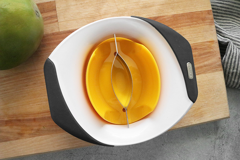 a mango slicer on a cutting board