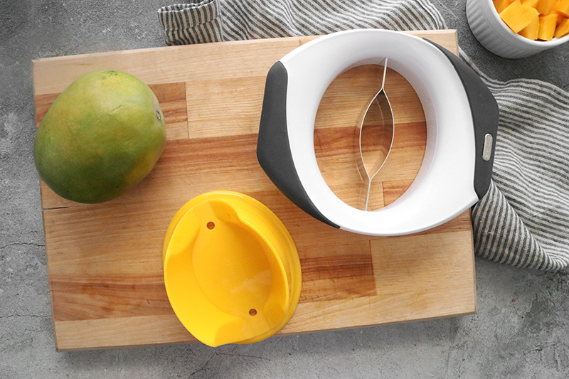 a mango slicer and holder with a mango on a cutting board