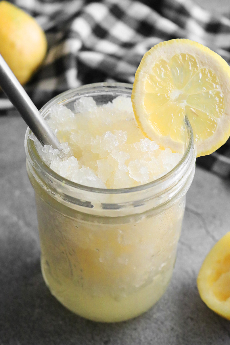 Frosty frozen lemonade in a ball jar glass with fresh lemon garnish