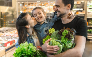 Happy husband and wife with a kid buys vegetables