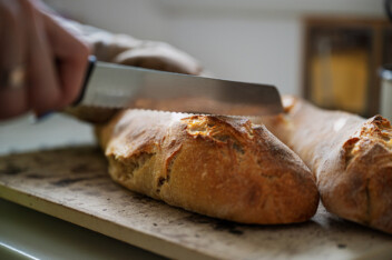 Knife cutting into freshly baked home made sourdough loaf of bread.