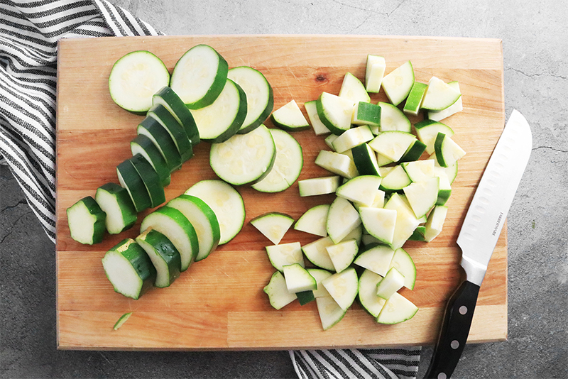 Chopped up zucchini on a cutting board with a knife