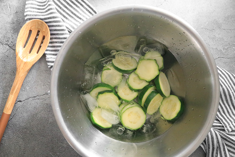 Zucchini in an ice bath to stop blanching process