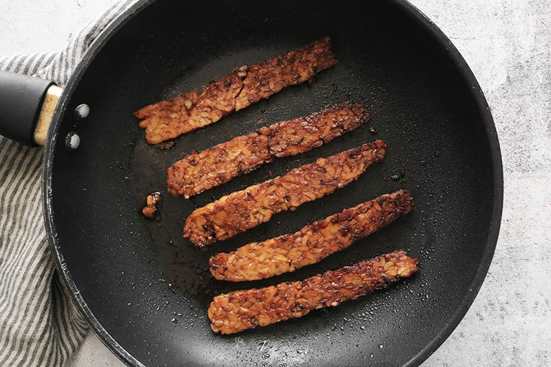 fried tempeh bacon in a pan