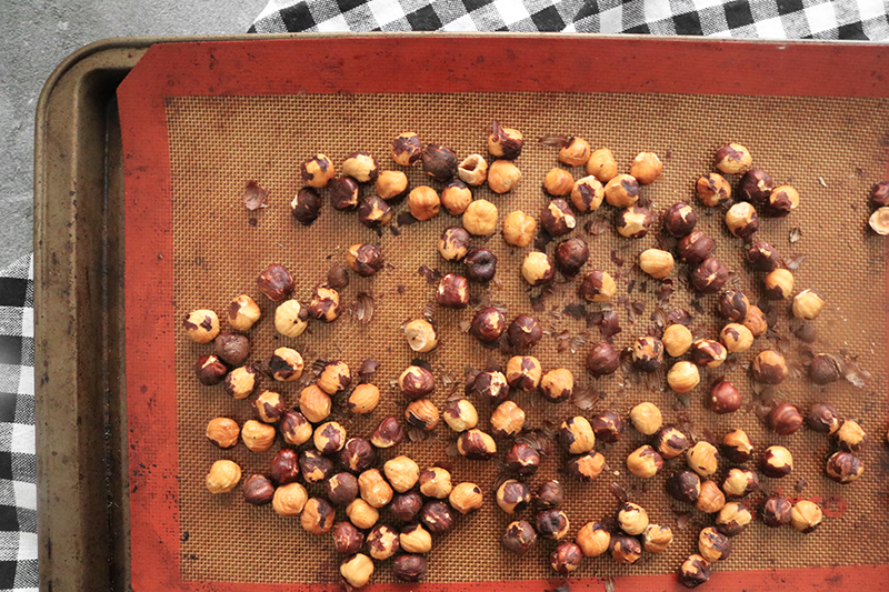hazelnuts spread out on a baking sheet, ready for roasting