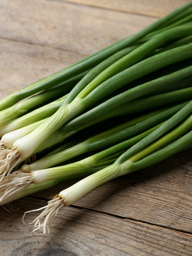 fresh green onions on wooden table