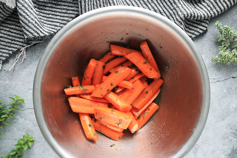 Carrots in a bowl with oil mixture and spices