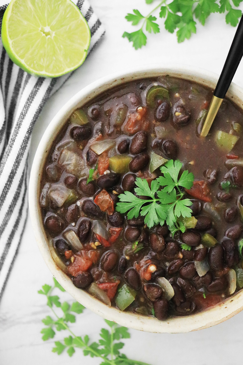 Black beans in a bowl with onions, bell peppers, and tomatoes, garnished with cilantro.