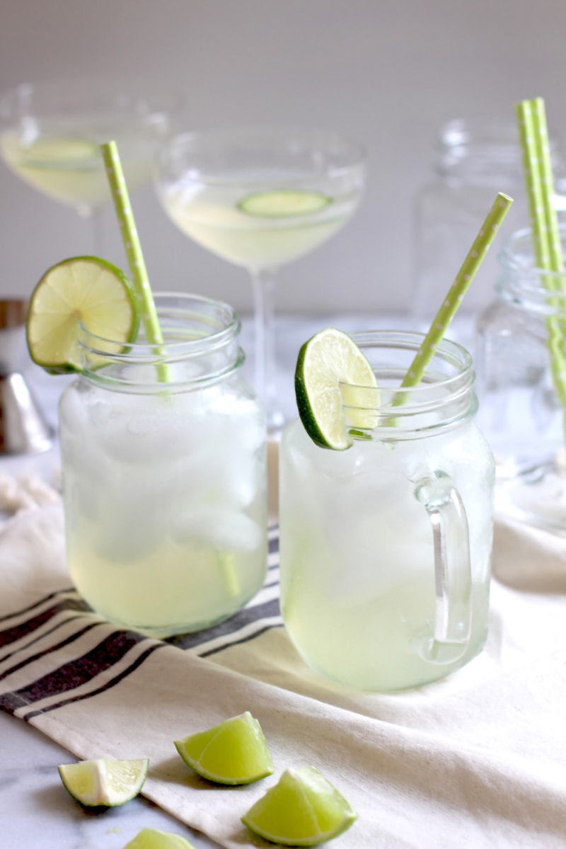 Glasses of mixed drinks made of cucumber infused vodka, dressed with sliced lime.
