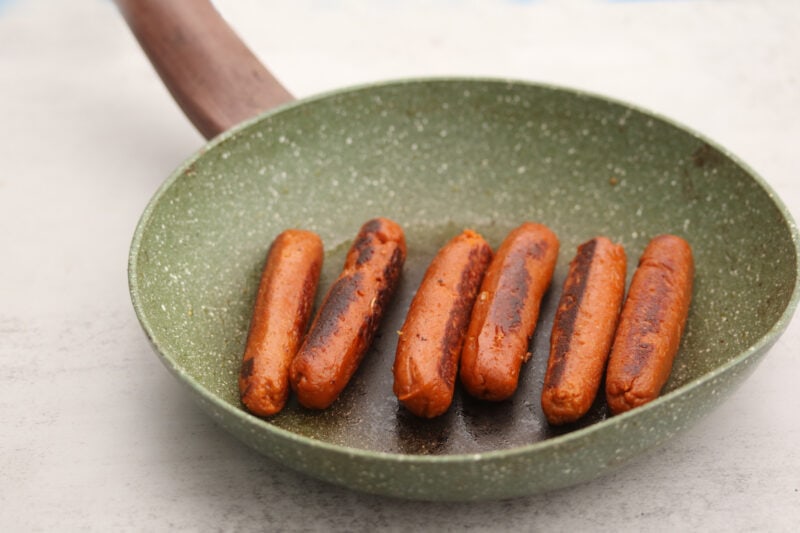 Vegan sausage in a skillet, browned on each side.