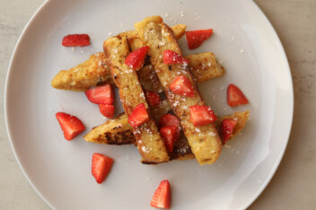 french toast sticks served with strawberries, powdered sugar and maple syrup