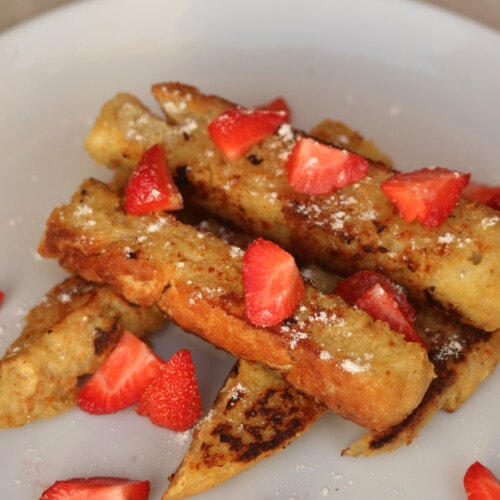 french toast sticks served with strawberries, powdered sugar and maple syrup