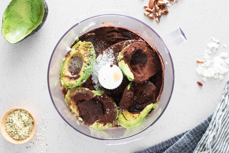 Ingredients for avocado chocolate pudding in a food processor.
