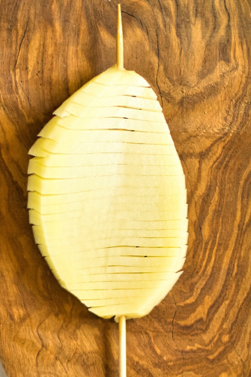 The grooved potato slice skewered vertically and twisted slightly to give an accordian shape.