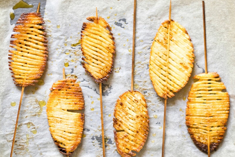 Baked accordion potato skewers on a baking tray lined with parchment paper.