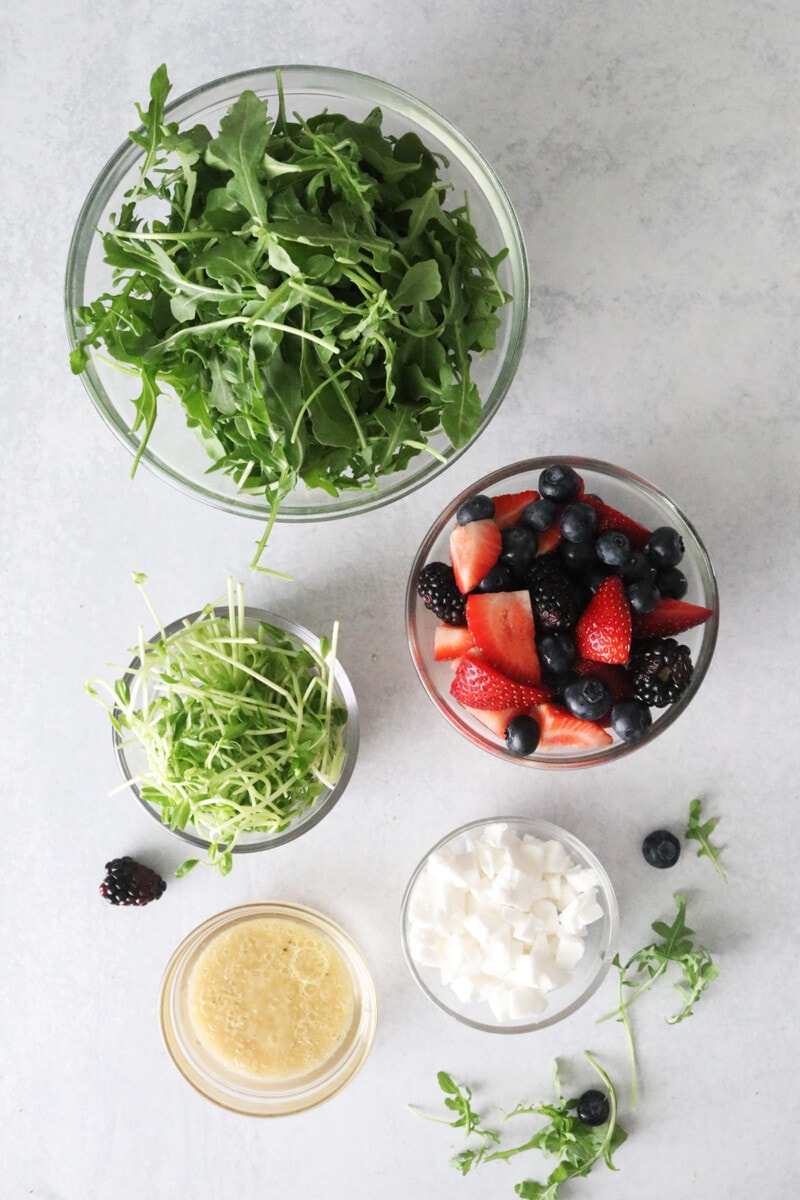 Berry Salad with microgreens ingredients: leafy greens, microgreens, vegan feta, black berries, strawberries, blueberries, and vinaigrette.