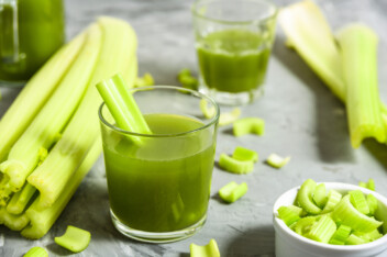 Celery juice in glass with celery stalks.