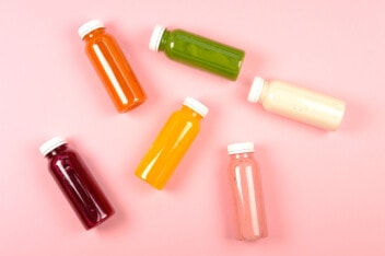A variety of fresh juices and smoothies in glass bottles.