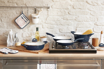A cookware set of kitchen pots and pans on a kitchen counter and stove.