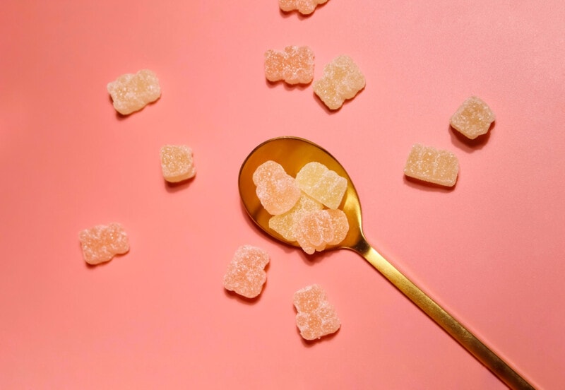 Gummy mushroom supplements on a plain background with a spoon.