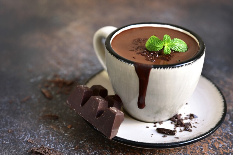 A cup of homemade hot chocolate, topped with fresh mint.