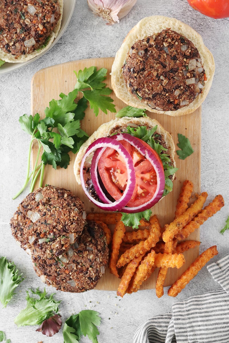 Vegan black bean burgers with oats, topped with red onion, tomato, and lettuce.