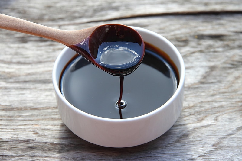 A spoonful of blackstrap molasses, serving from a small bowl.