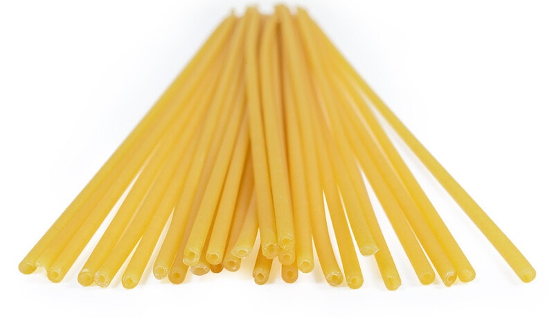 Bundle of uncooked long tubular bucatini pasta, also known as perciatelli on a white background.