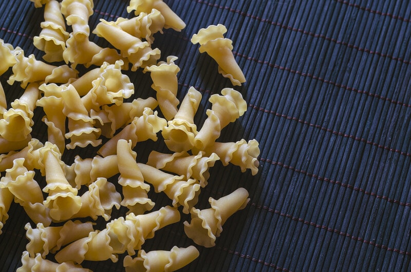 Uncooked campanelle pasta on a dark bamboo napkin.