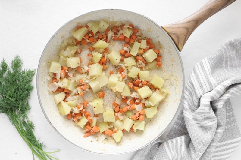 Cook onions, carrots, and potatoes in a skillet