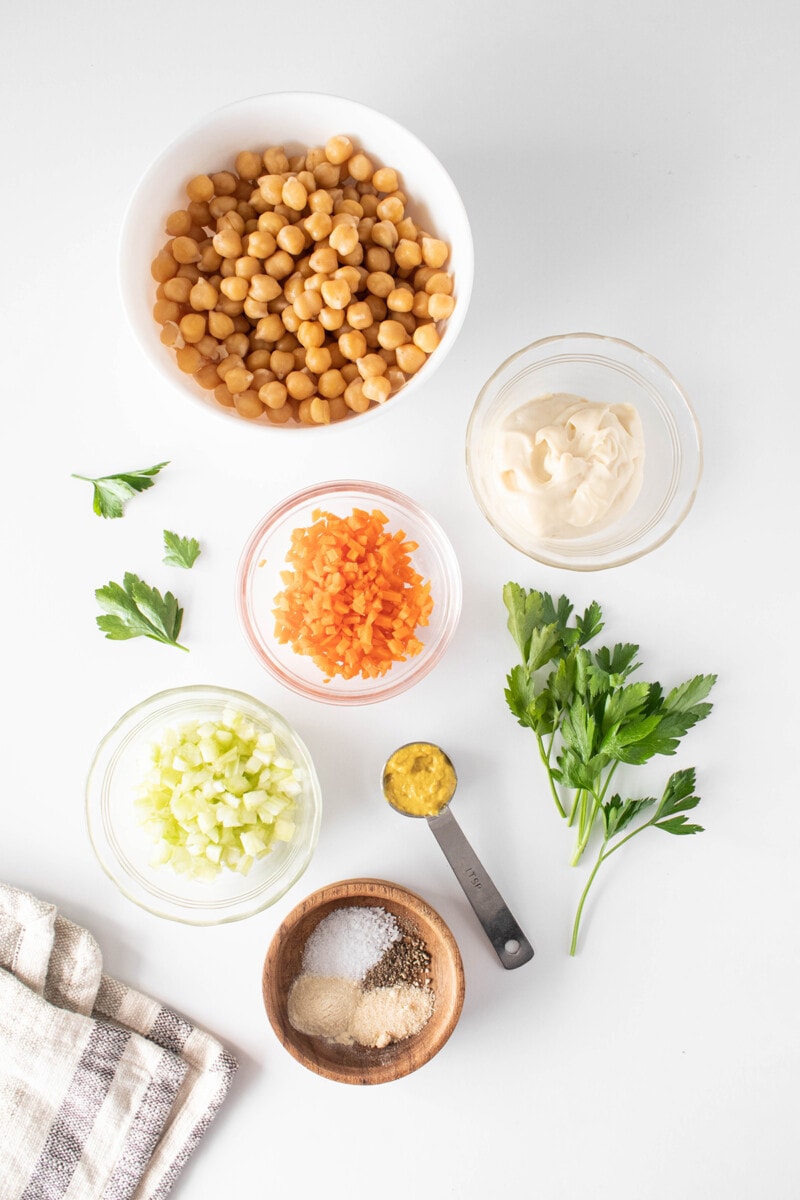 Ingredients for chickpea salad sandwich: Chickpeas, vegan mayo, mustard, minced celery and carrots, garlic powder, onion powder, salt, and pepper.