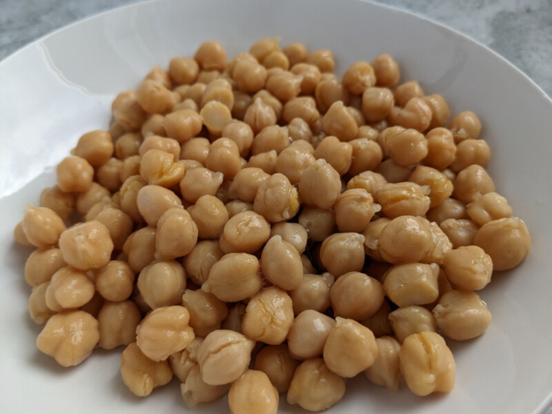 Close-up view of cooked chickpeas in a white bowl.