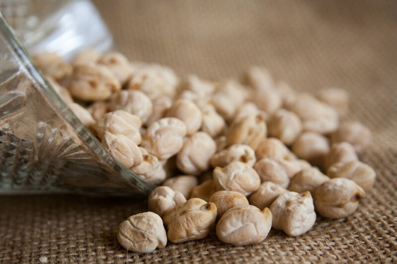 Garbanzo Beans (Chickpeas) emptying out of a glass bowl onto a piece of burlap