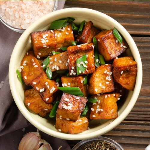 crispy stir fried tofu with chives on a wooden table