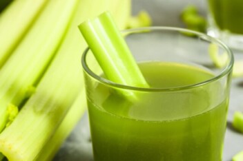 Celery juice in glass with celery stalks.