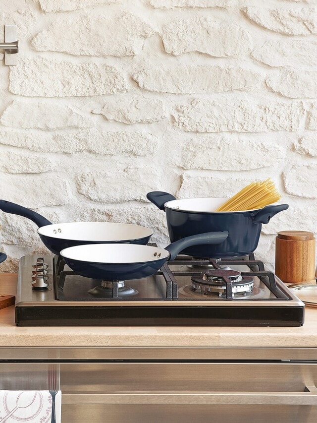 A cookware set of kitchen pots and pans on a kitchen counter and stove.