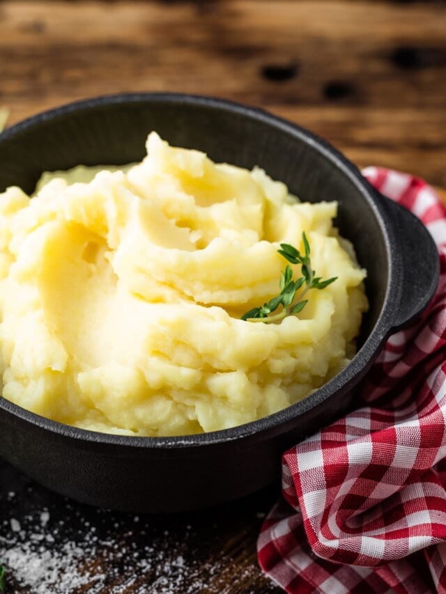 Mashed potatoes in a cast iron crock on a wooden table