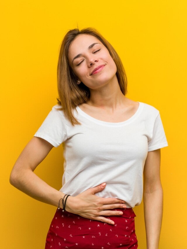 Woman with good digestion on yellow background.