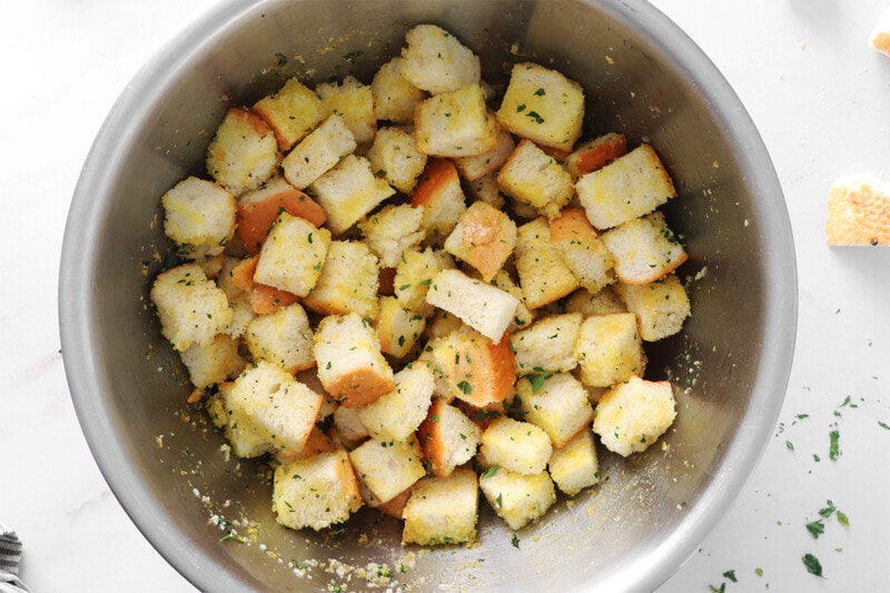 Croutons in a stainless steel bowl before baking.